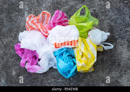 Colorful plastic bags on dirty cement floor background. Stock Photo