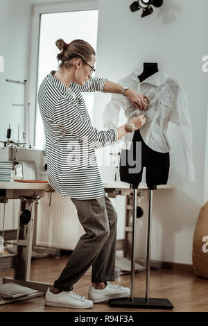 Handsome young fashion dressmaker in white snickers working with a dummy Stock Photo