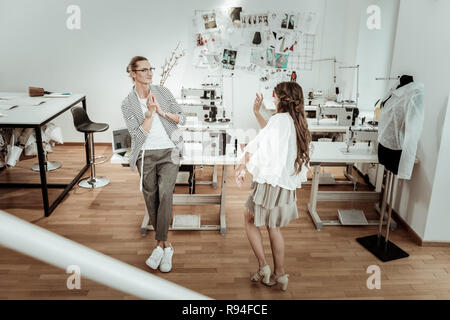 Tall handsome dressmaker feeling wonderful with the beautiful model in a beige dress Stock Photo