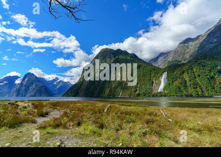 reflections of mountains in the water and a waterfall at famous milford sound,  fiordland, southland, new zealand Stock Photo