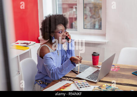 African-American interior designer wearing blue sweater feeling surprised Stock Photo