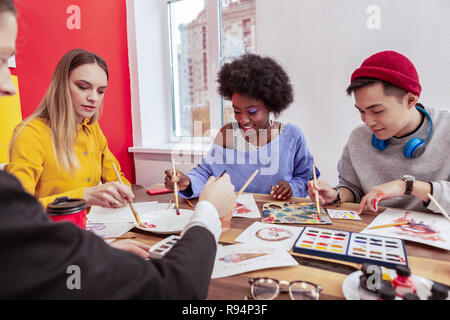 Two male and two female art students painting together in the class Stock Photo