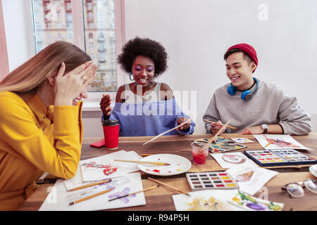 Three young artists laughing while having a little break Stock Photo