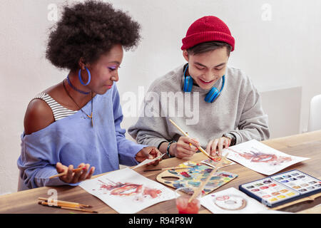 Couple of art students mixing colors while drawing together Stock Photo