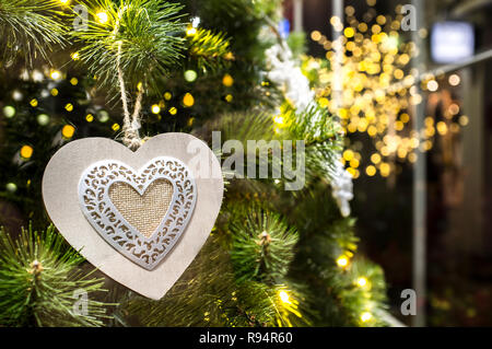 Heart-shaped hanging decoration the Christmas tree. Yellow bokeh points as background Stock Photo