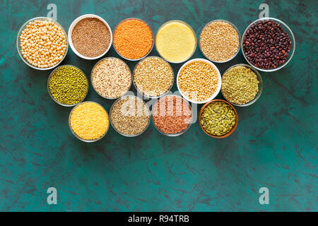 Flat lay set of glass bowls with superfoods on textured emerald background. Stock Photo