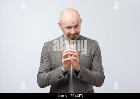 Cunning tricky mature man thinking with hand together over white background. Stock Photo