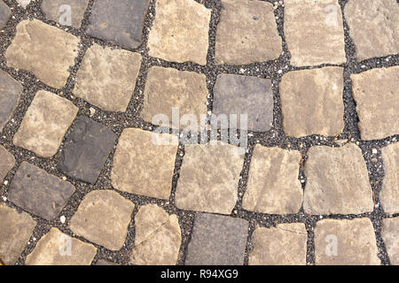 Random size and color cobblestones laid in curves in the street Stock Photo