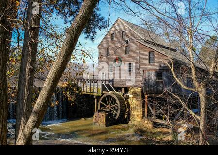 Old mill decorated with a holiday wreath  for Christmas as seen through the trees of the forest at Historic Yates Mill County Park in Raleigh North Ca Stock Photo