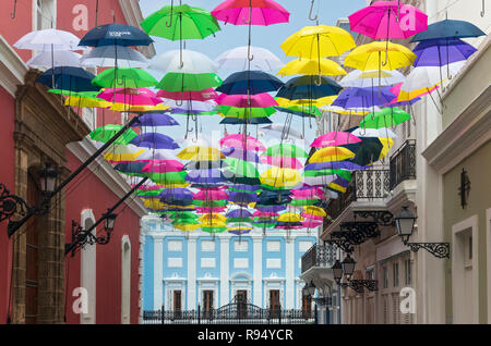 colorful umbrellas suspended above streets of old san juan and the governor’s mansion or santa catalina palace in background Stock Photo
