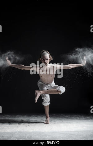 Sporty young man practicing yoga, doing balance exercise on leg, balancing posture Stock Photo