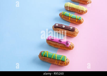 Row of eclairs on pink-blue background with copy space Stock Photo