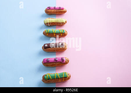 French eclairs on pink-blue background with copy space Stock Photo