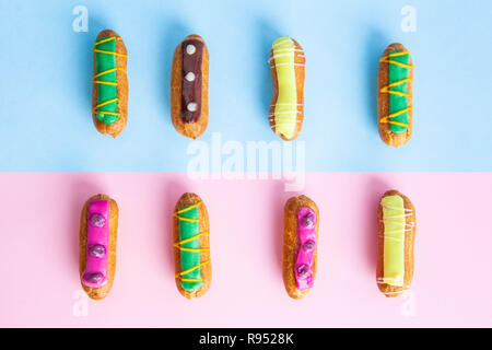 Rows of decorated French eclairs on pink and blue backgrounds Stock Photo