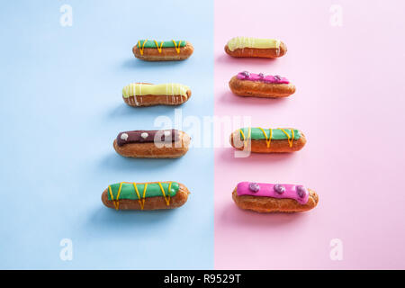 Decorated colorful eclairs on pink and blue divided background Stock Photo