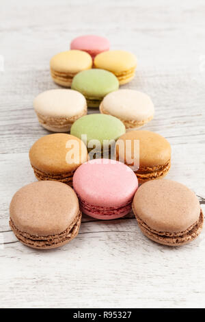Rows of colorful macarons on wooden table with shallow focus Stock Photo