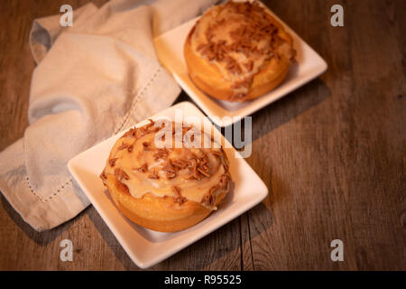 sweet buns with cinnamon and toffee icing on a wooden table Stock Photo