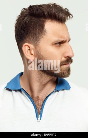 Serious man standing, looking at camera isolated on white studio background. Beautiful, young face. male half-length portrait. Human emotions, facial expression concept. Stock Photo