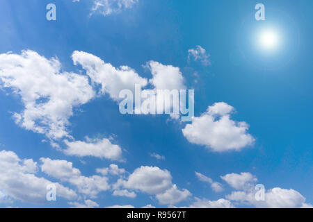 White fluffy clouds and sunshine on in front of blue sky. Stock Photo