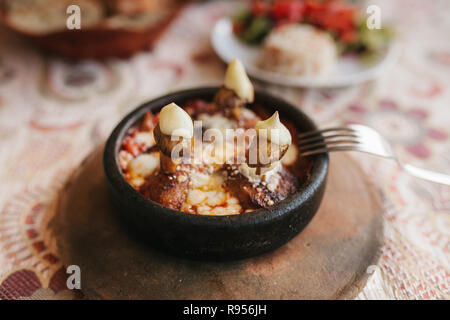 Close-up - dish with mushrooms and white sauce in bowl on wooden stand. Restaurant menu. Traditional Turkish food. Stock Photo