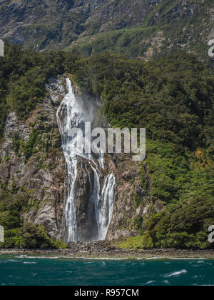 Stirling Falls releases a torrent of water down a rocky mountainside into Milford Sound in Fiordland National Park on the South Island of New Zealand Stock Photo