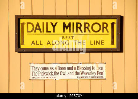Old metal advertising panel for the Daily Mirror newspaper on display on wall at railway station Stock Photo
