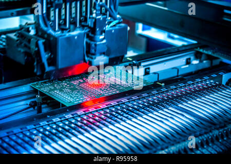 Electronic circuit under surface-mounting machine. Shot in red and blue tints. Surface-mount technology as a producing of electronic circuits. Components placed onto the surface of printed elements. Stock Photo