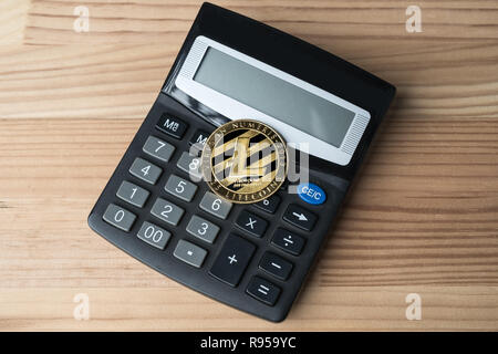 Golden physical Litecoin on calculator on wooden background. Cryptocurrency market numbers abstract concept. Stock Photo