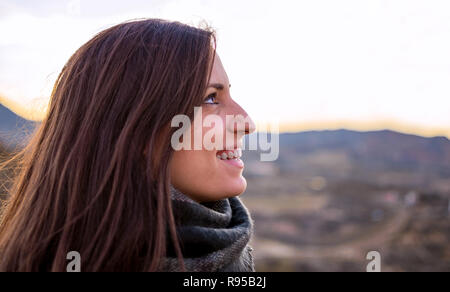 Smiling woman portrait side view. Young caucasian Spanish girl against agriculture fields. Freedom in nature. Stock Photo