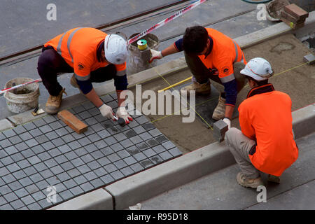 Tilers laying pavers on a city street in Newcastle, NSW, Australia. Stock Photo