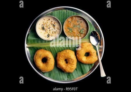 Medu vada is a South Indian breakfast snack made from Vigna mungo. It is usually made in a doughnut shape, with a crispy exterior and soft interior. A popular food item in South Indian cuisine it is generally eaten as a breakfast or a snack. Stock Photo