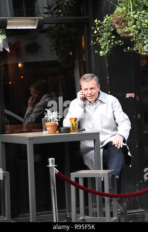 Madness Ska and pop group lead singer and song writer Graham McPherson Known by the stage name Suggs pictured having a beer in London on 18th March 2014. Musician. Radio presenter. Actor. Suggs. Band Madness. Ska Genre. Stock Photo