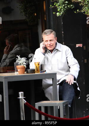 Madness Ska and pop group lead singer and song writer Graham McPherson Known by the stage name Suggs pictured having a beer in London on 18th March 2014. Musician. Radio presenter. Actor. Suggs. Band Madness. Ska Genre. Stock Photo