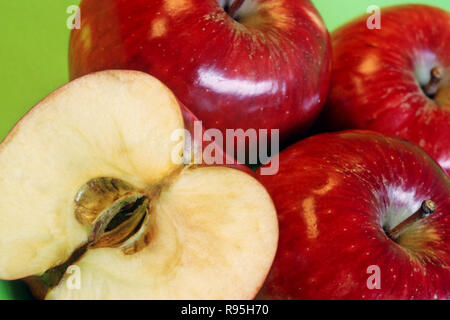 Apple one cut and three full uncut apples on green background Stock Photo