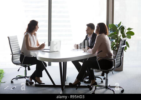 Multi-ethnic business partners negotiating sitting at desk Stock Photo