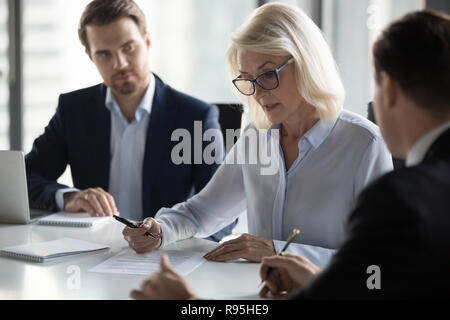 Concentrated aged businesswoman checking agreement before signin Stock Photo