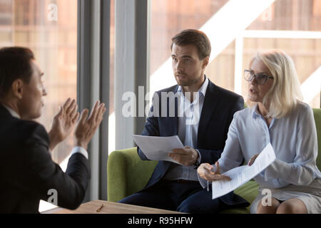 Angry financier director pointing on document showing it to coll Stock Photo