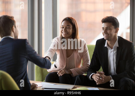Happy multiracial businesspeople shaking hands during corporate  Stock Photo