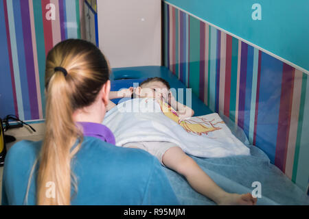 Medical clinic. An occupation with child with cerebral palsy. A nurse standing in front of the baby Stock Photo