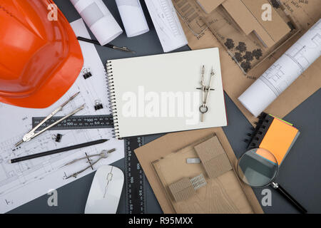 Workplace of architect - blank note pad, construction drawings and engineering tools, magnifying glass, helmet on grey background Stock Photo