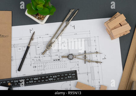 Workplace of architect - model house from wooden blocks, construction drawings, engineering tools on grey background Stock Photo