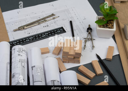 Workplace of architect - model house from wooden blocks, construction drawings, engineering tools on grey background Stock Photo