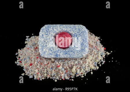 Powder and tablets for the dishwasher on the kitchen table. Cleaning agent for household dishwashers. Dark background. Stock Photo