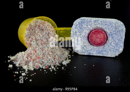 Powder and tablets for the dishwasher on the kitchen table. Cleaning agent for household dishwashers. Dark background. Stock Photo