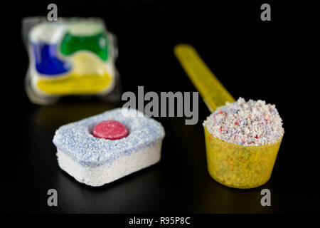 Powder and tablets for the dishwasher on the kitchen table. Cleaning agent for household dishwashers. Dark background. Stock Photo