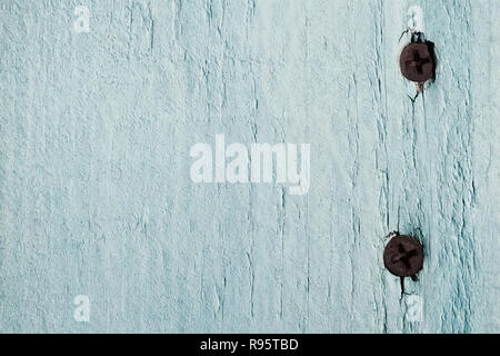 The texture of a board with two rusty nails is painted light-turquoise color Stock Photo