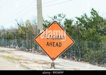 Flagman ahead traffic road sign in red, orange color, signal for drivers on overseas highway road, US1 about utility, construction, repair work, worke Stock Photo