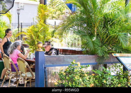Key West, USA - May 1, 2018: Waiter, people, senior couple, sitting by table, chairs, outside outdoors in Blue Macaw Island Eats, Bar, restaurant, ord Stock Photo