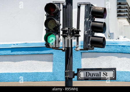 Closeup of Duval St street road traffic sign in old town of Key West, Florida, Fl in city, urban view with green light against blue, white building in Stock Photo