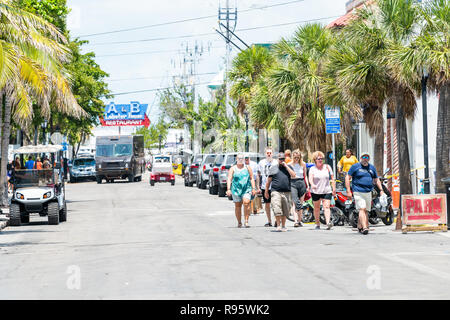 Key West, USA - May 1, 2018: Group of people, family, tourists, couple walking on sidewalk of urban street road in Florida keys city on summer day, pa Stock Photo